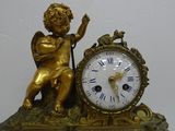 a gold statue of an angel with a clock on a table