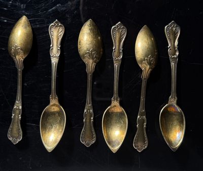 six spoons are lined up in a row on a black surface