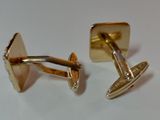two pairs of gold cufflinks on a white surface
