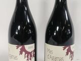 two bottles of red wine sitting next to each other on a white surface