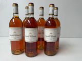 four bottles of wine are lined up on a white surface
