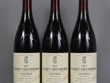 three bottles of wine sit on a glass table in front of a gray background