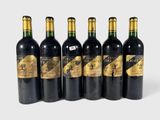 six bottles of wine are lined up on a white surface