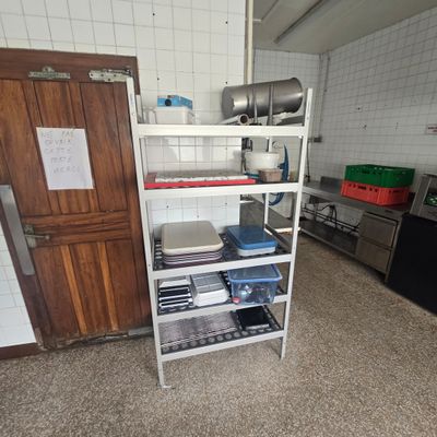 a kitchen with a stove, refrigerator, sink, and shelves