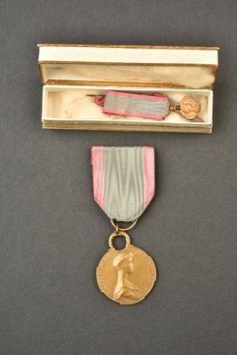 une médaille dans un coffret en bois, accompagnée d'un ruban et contenant un ruban