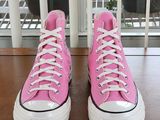 pink converses with white laces are sitting on a wooden table