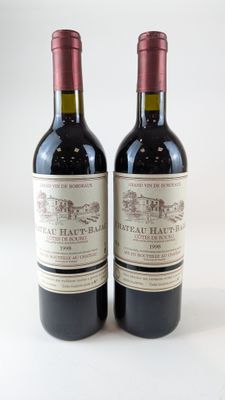 deux bouteilles de vin rouge posées l'une à côté de l'autre sur une surface blanche