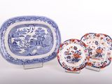trois assiettes bleues et blanches et un plat de service posés sur un plan de travail blanc