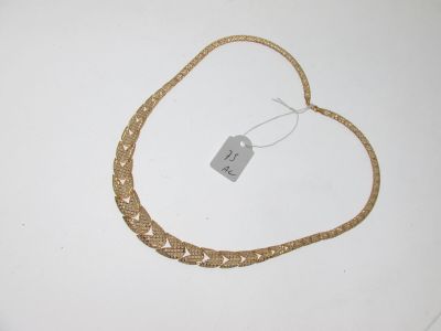 un collier en or posé sur une surface blanche, avec une étiquette de prix