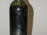 une bouteille de vin posée sur une table, dont l'ombre se projette sur le mur