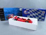 une voiture de course rouge dans une boîte blanche à côté d'une boîte bleue