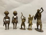 quatre figurines en bronze représentant des personnes tenant une pancarte à la main