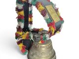a bell with a wreath around it on a white surface