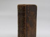 an old brown book sitting on top of a white surface