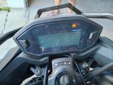 a close up of a motorcycle dashboard with a person standing in the background
