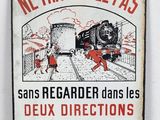 un vieux panneau métallique représentant un train sur les rails et des gens sur le quai
