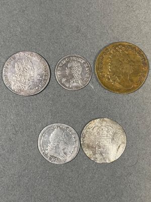 quatre types différents de pièces d'argent et d'or sur une surface grise
