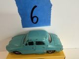 une petite voiture bleue posée sur une boîte jaune sur laquelle figure le chiffre 6