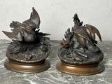 deux statues d'oiseaux en bronze posées sur une table en marbre