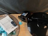 une table sur laquelle se trouvent un ventilateur, une télécommande et d'autres objets