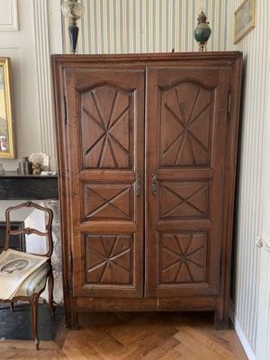 une grande armoire en bois dans une pièce où se trouve une chaise