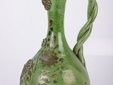 un vase vert posé sur une surface blanche