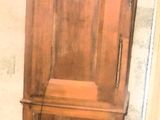 une horloge de parquet en bois posée à même le sol près d'une porte