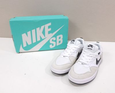 des chaussures Nike blanches et noires avec une boîte posée sur une table