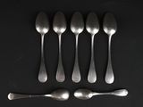 six spoons and a spoon rest on a black surface