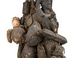 une statue représentant un homme assis sur un tas de chaussures