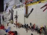 de nombreux outils accrochés à un panneau perforé fixé au mur