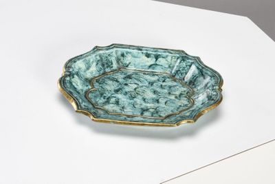 une assiette verte et dorée posée sur un fond blanc