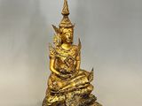 une statue en or représentant une personne assise sur une pile de livres