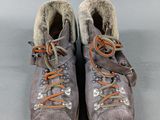 two pairs of hiking boots with orange laces on them on a gray surface