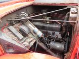 an old red car with a bunch of wires attached to it