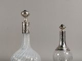 deux vases en verre avec un couvercle en argent et une bouteille en verre surmontée d'un oiseau