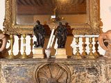 une cheminée sur laquelle sont posés des bougies, des statues et un miroir