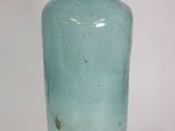 a green glass bottle that is sitting on a table