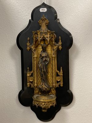 une horloge noire et dorée accrochée au mur, à côté d'un mur blanc