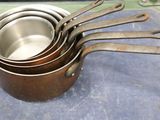 five pots with spoons in them sitting on a counter
