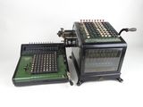 an old fashioned calculator sitting next to another old type of calculator