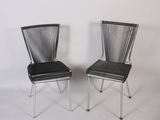 pair of black metal chairs against a white wall with a white background