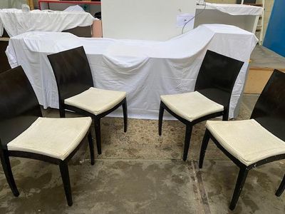 quatre chaises noires et blanches recouvertes de housses blanches dans une pièce