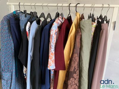 beaucoup de vêtements suspendus à une étagère dans une pièce