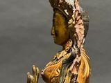 statue of a woman sitting on a rock with a crown on her head
