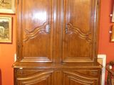 a large wooden armoire in a room with pictures on the wall