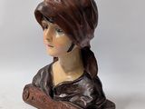 statue of a woman with a hat on her head sitting on a wooden block