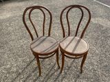 two wooden chairs sitting next to each other in a parking lot