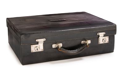 une valise noire posée sur une surface blanche
