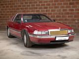 a red car that is parked in front of a brick wall